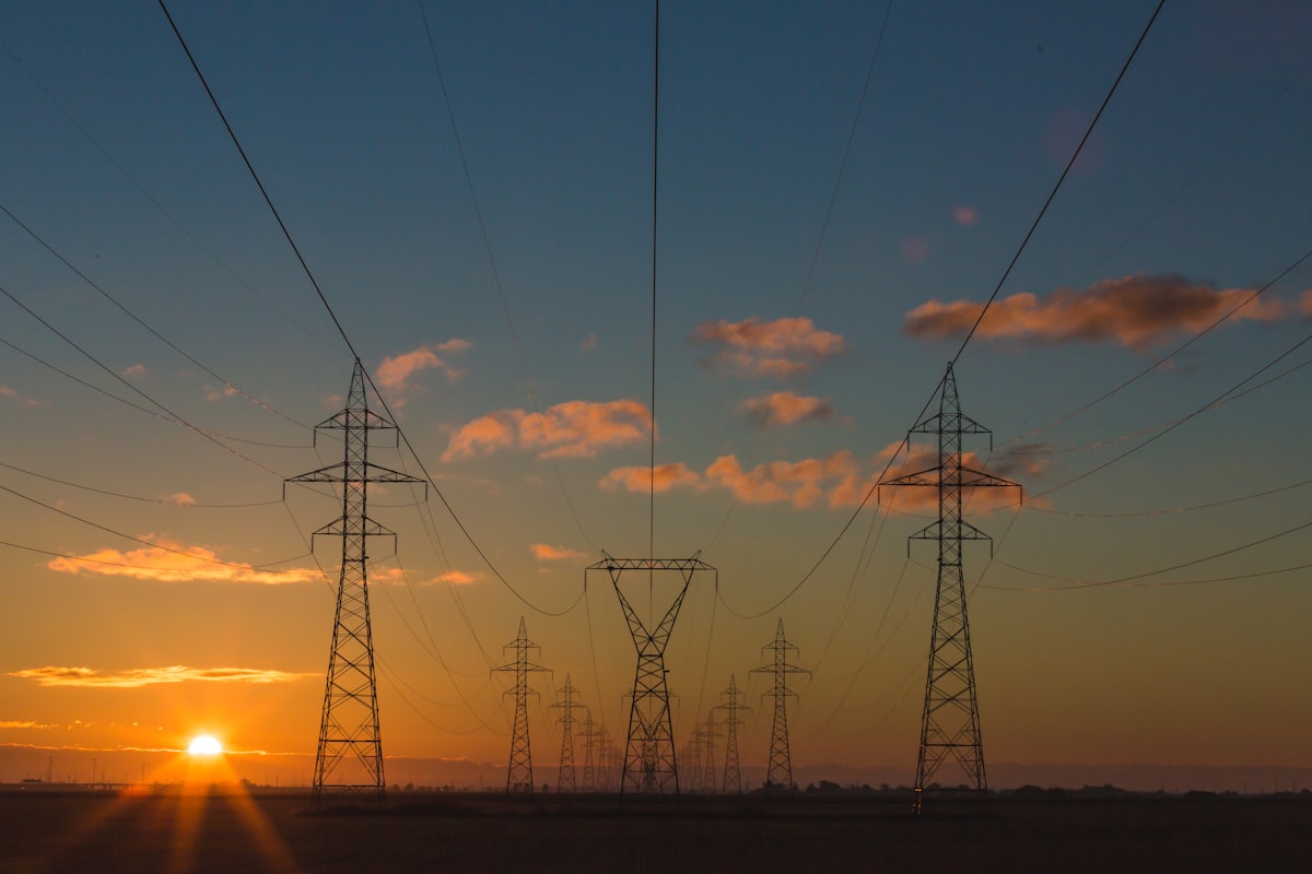 High-voltage transmission towers at dusk, the network constraint behind most curtailment